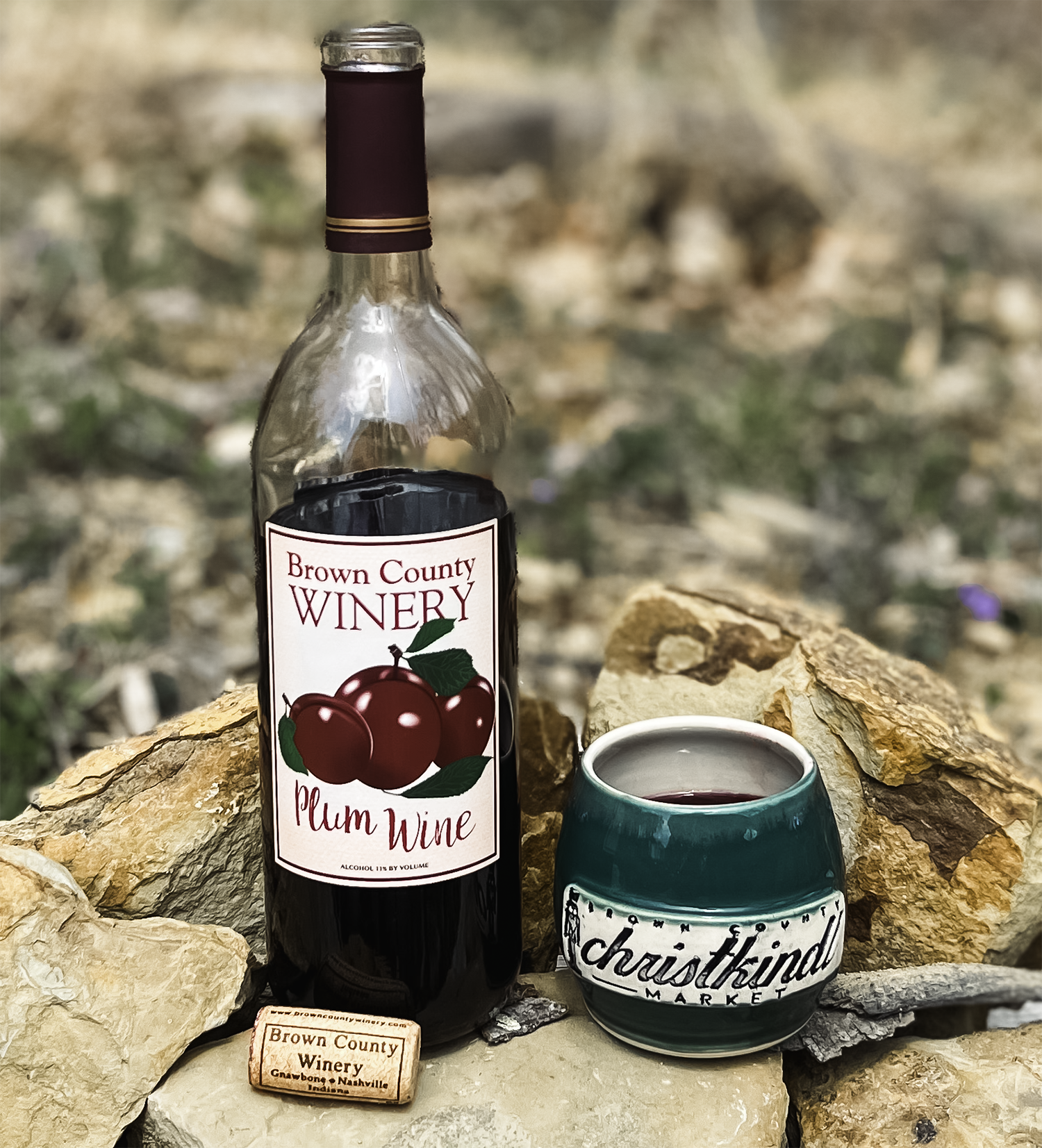 Photo of 2022 Brown County Christkindl Market mug next to a bottle of Brown County Plum Wine